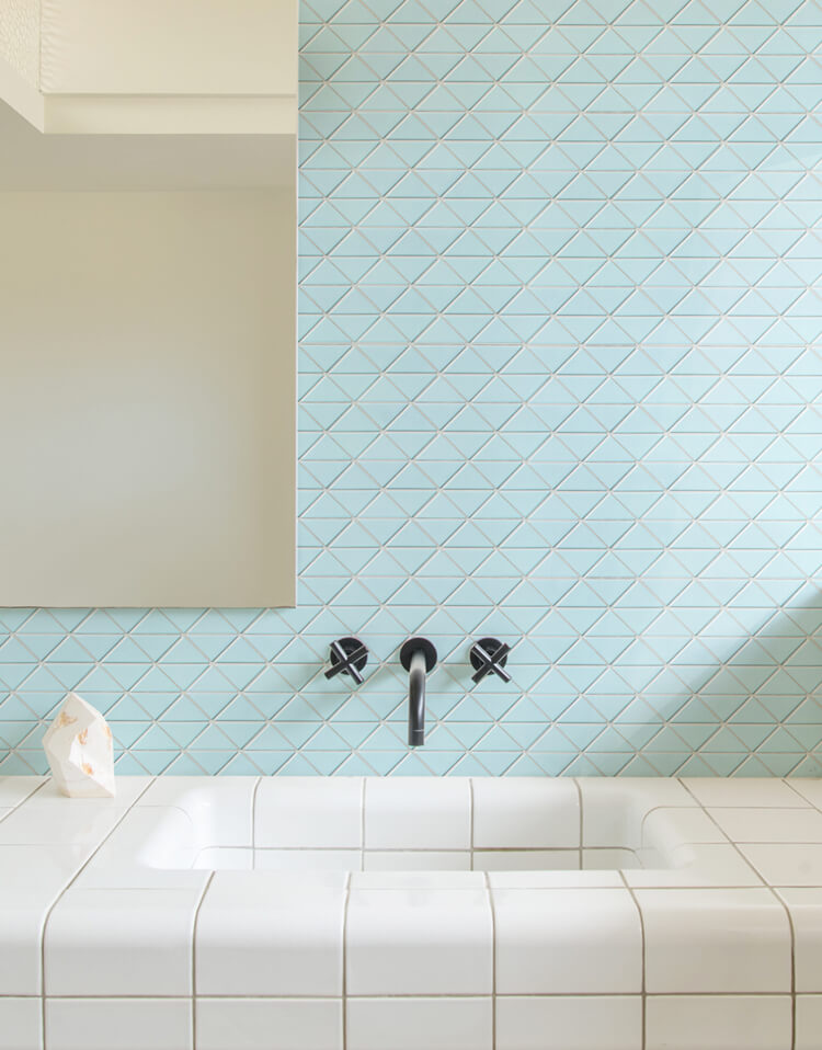 clean bathroom design with light blue triangle tiled wall and white tiled wash basin